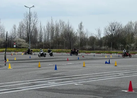 Cursanți pe motociclete printre conuri, exerciții pe poligon